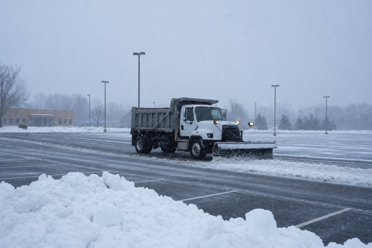 Commercial plow truck clearing snow from a business parking lot in Greater Binghamton NY during a winter storm